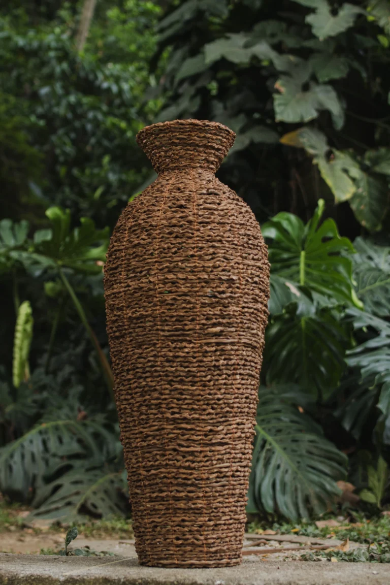 Jarrón artesanal tejido en fibra natural en jardín tropical – Areito Gallery