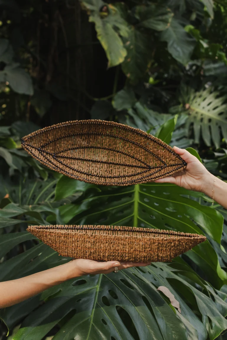 Manos sosteniendo bandejas artesanales tejidas en forma de hoja – Areito Gallery